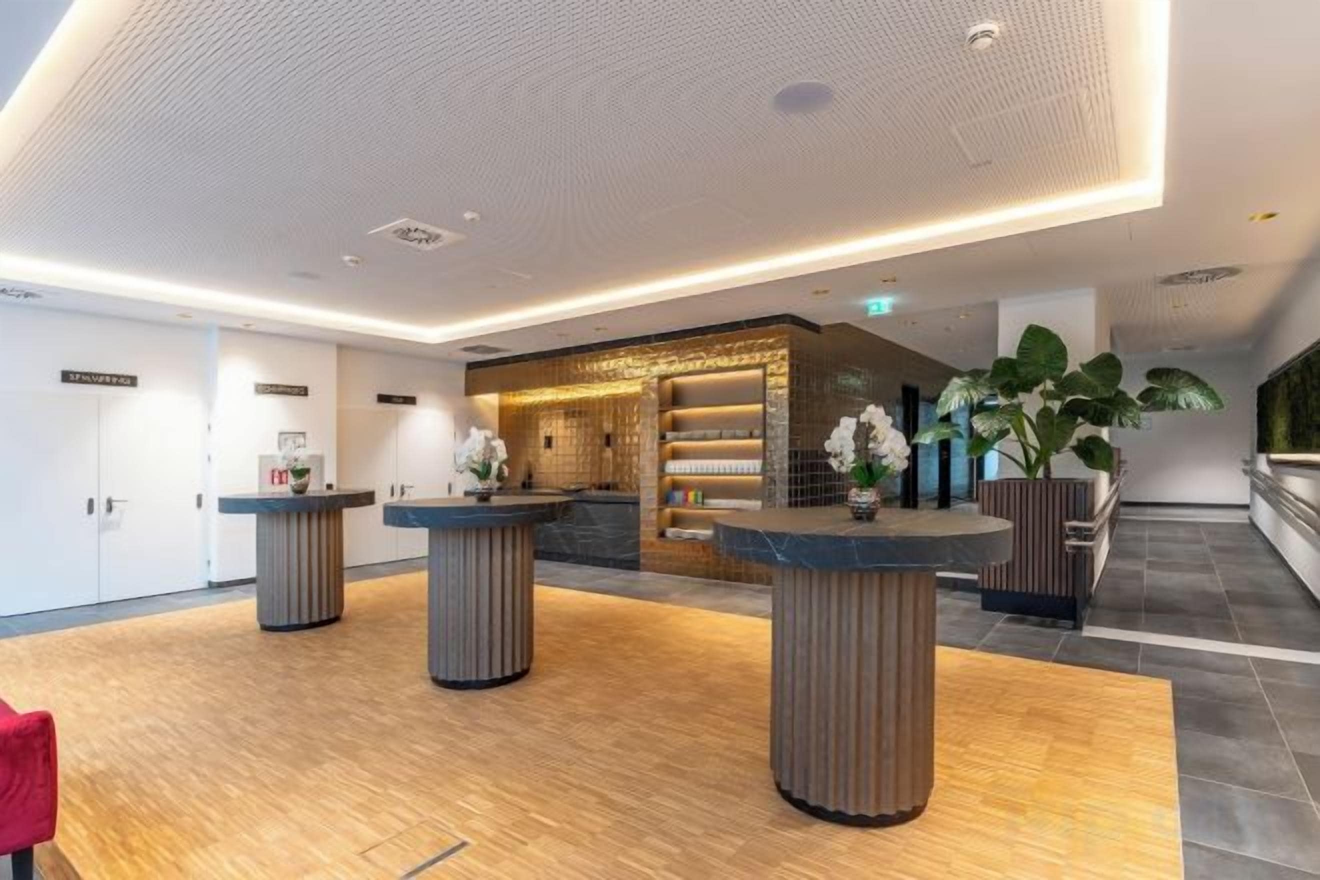 A modern hotel lobby with reception counters, a reception desk, and a large potted plant.