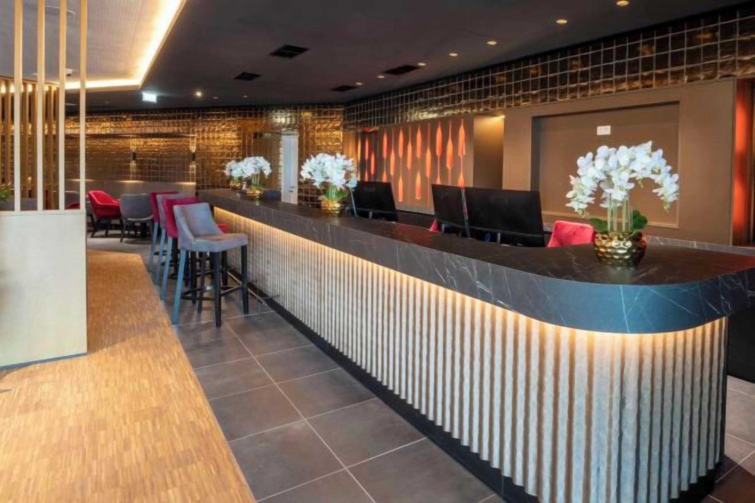 A reception area with a curved counter, seating, and decorative plants.