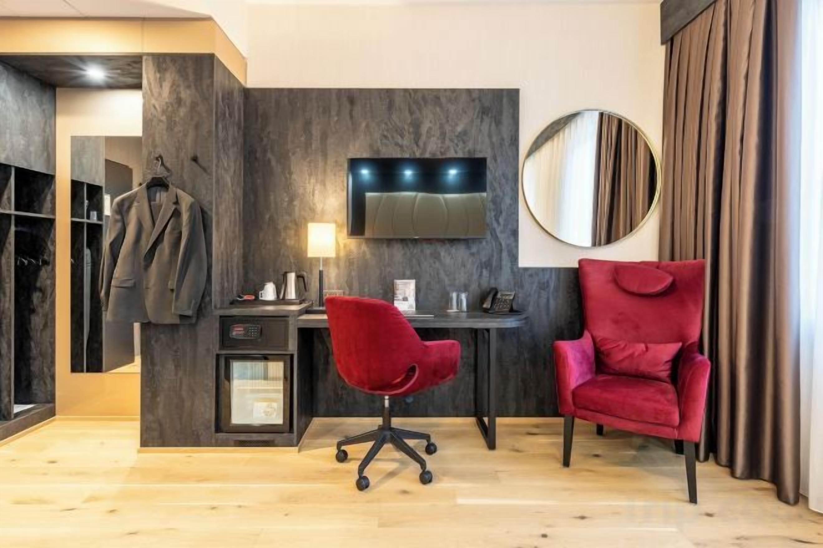 Quarto moderno com escrivaninha, duas cadeiras, televisão e guarda-roupa.