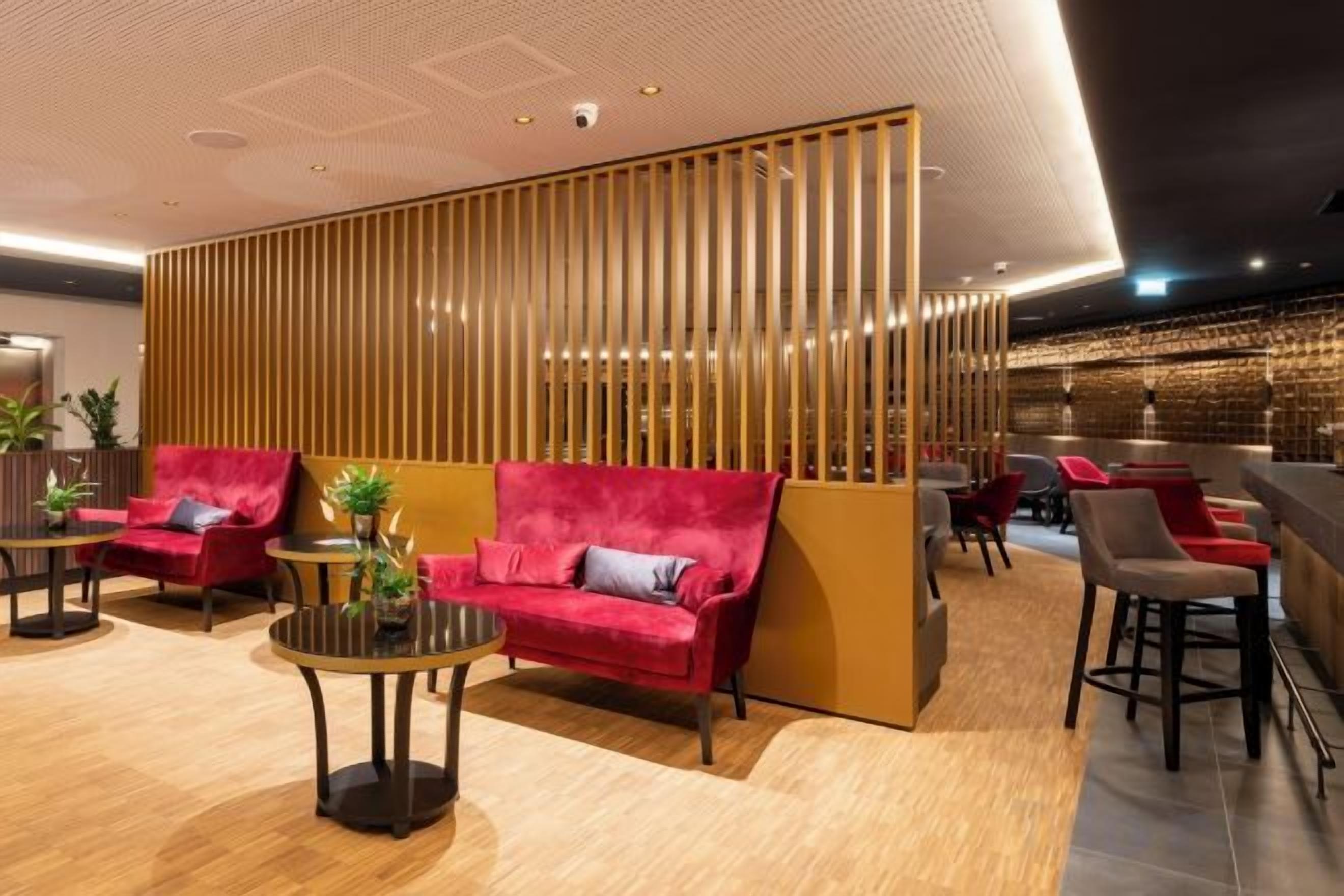 A modern lobby with seating areas, a reception desk, and a decorative wall.