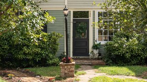 Une maison à deux étages avec un porche à l’avant, un chemin menant à la porte et une boîte aux lettres.