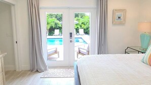 Una camera da letto con un letto, vista su una piscina e una porta che dà all'esterno.