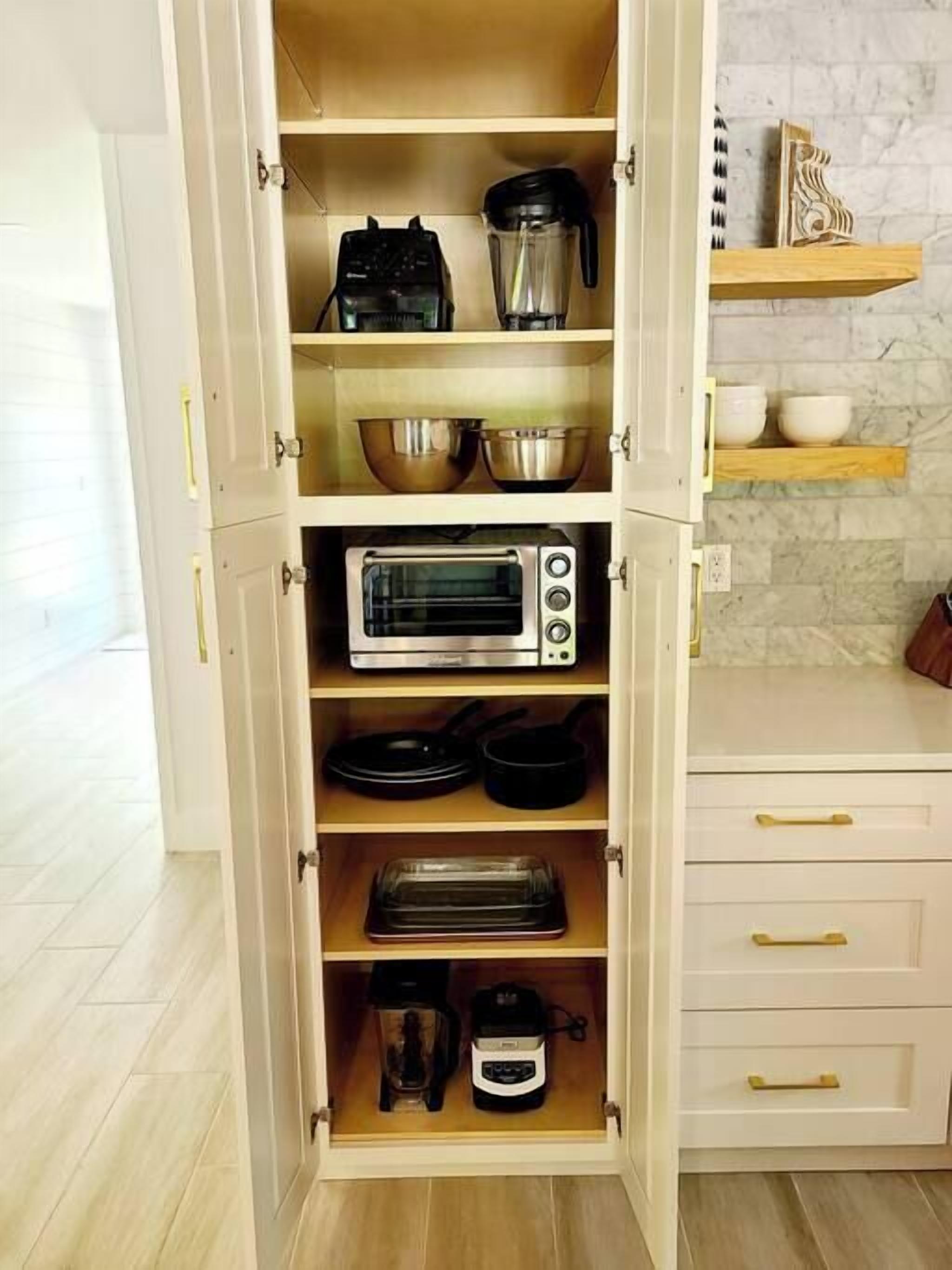 Una cocina con horno tostador, cafetera y licuadora en los estantes.