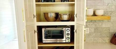 Una cocina con horno tostador, cafetera y licuadora en los estantes.
