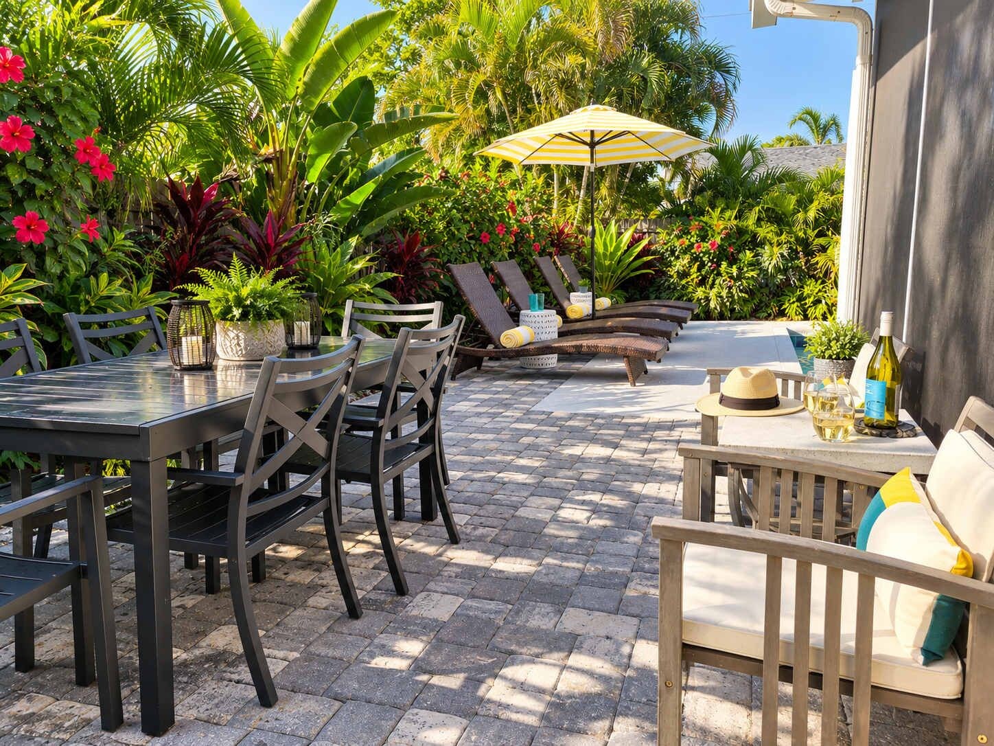An outdoor patio with a table and chairs, a lounge area with sun loungers, and a potted plant.