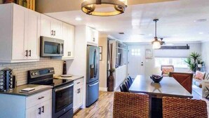A modern kitchen with white cabinets, stainless steel appliances, and a central island with seating. - 677 Beach Break ·Beautiful 3/3 Home w/ Heated Pool (Naples)