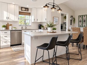 A modern kitchen with white cabinetry, a central island, bar stools, and pendant lighting. - 677 Beach Break ·Beautiful 3/3 Home w/ Heated Pool (Naples)