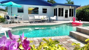 Ett hus med en swimmingpool, en uteplats med solstolar och utsikt över havet.