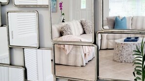Una habitación con una cama, una mesita redonda y un espejo que refleja el espacio.