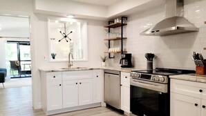 Una cocina moderna con armarios blancos, horno integrado y cafetera.