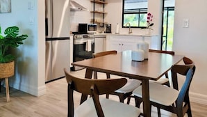 A modern kitchen with a dining area, featuring a refrigerator, microwave, and a window with a view. - 835 Villas of GulfShore | Walk 2 Mercato & Beaches (Naples)