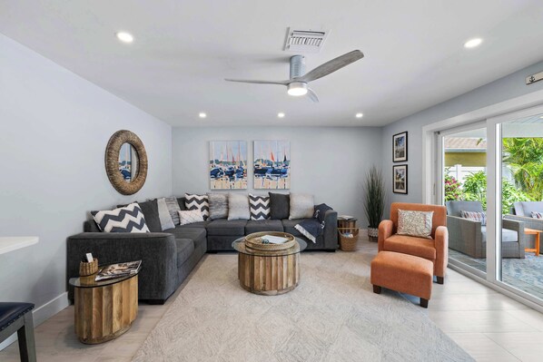 A modern living room with a grey sofa, a round wooden coffee table, and an orange armchair.