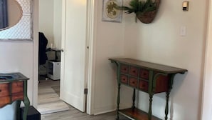 Ein Flur mit Holzboden, einem grünen Konsolentisch, einer Wandpflanze und einem gerahmten Bild.