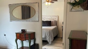 Ein Schlafzimmer mit Bett, Schminktisch, Spiegel und Deckenventilator.
