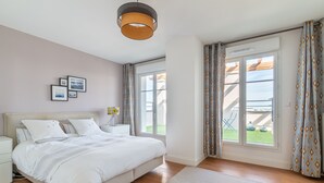 Un dormitori amb un llit gran, una tauleta de nit, una finestra amb cortines i vista a l'exterior.