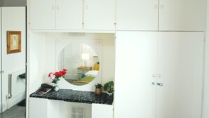 A compact, white room with a small kitchenette area, a mirror, and a framed picture on the wall. - Stylish 2 Bed Room Apartment 3 Sleep Free Wifi & p (Newport)
