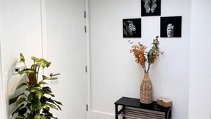 A room with a white door, a potted plant, a black console table, and three black-and-white framed artworks on the wall. - Superb 2 Beds Flat in The heart ofLondon! (London)