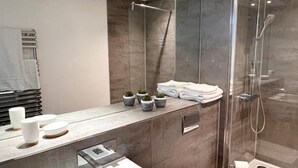 A modern bathroom with a glass-enclosed shower, a vanity with a sink and towel rack, and small potted plants on the counter. - Superb 2 Beds Flat in The heart ofLondon! (London)
