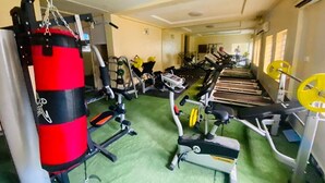 Un gimnasio con varios equipos de ejercicio, incluyendo un saco de boxeo rojo, cintas de correr y máquinas de pesas.