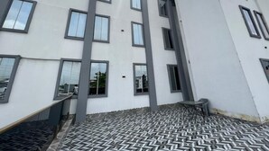 Un edificio moderno con techo plano, múltiples ventanas y suelo de baldosas estampadas.