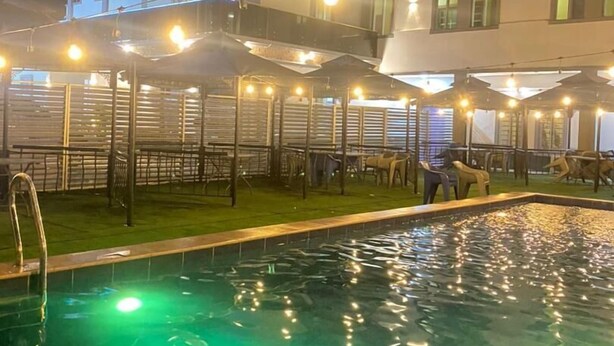 Un hotel con piscina, mobiliario exterior y una fachada bien iluminada.