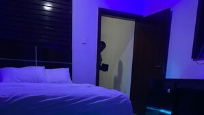 Un dormitorio con cama, una puerta y un escritorio con computadora.