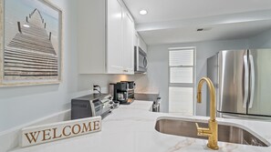 Enjoy cooking in this well-equipped kitchen with a stainless steel refrigerator, oven, and coffee maker.