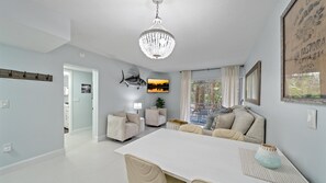 Relax in the spacious living room with a comfortable seating area, dining table, and large window offering a view of the outdoors.