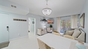 A spacious living area with a white dining table, beige sofas, and a chandelier. - Beach Castle Resort, 1st Floor, Pool, Walk to Beach/Bay (Longboat Key)