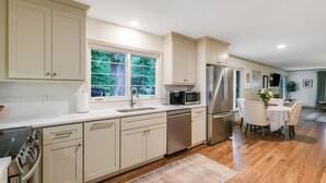 Une cuisine moderne avec des meubles de couleur beige, des appareils en acier inoxydable et un coin repas comprenant une table et des chaises.