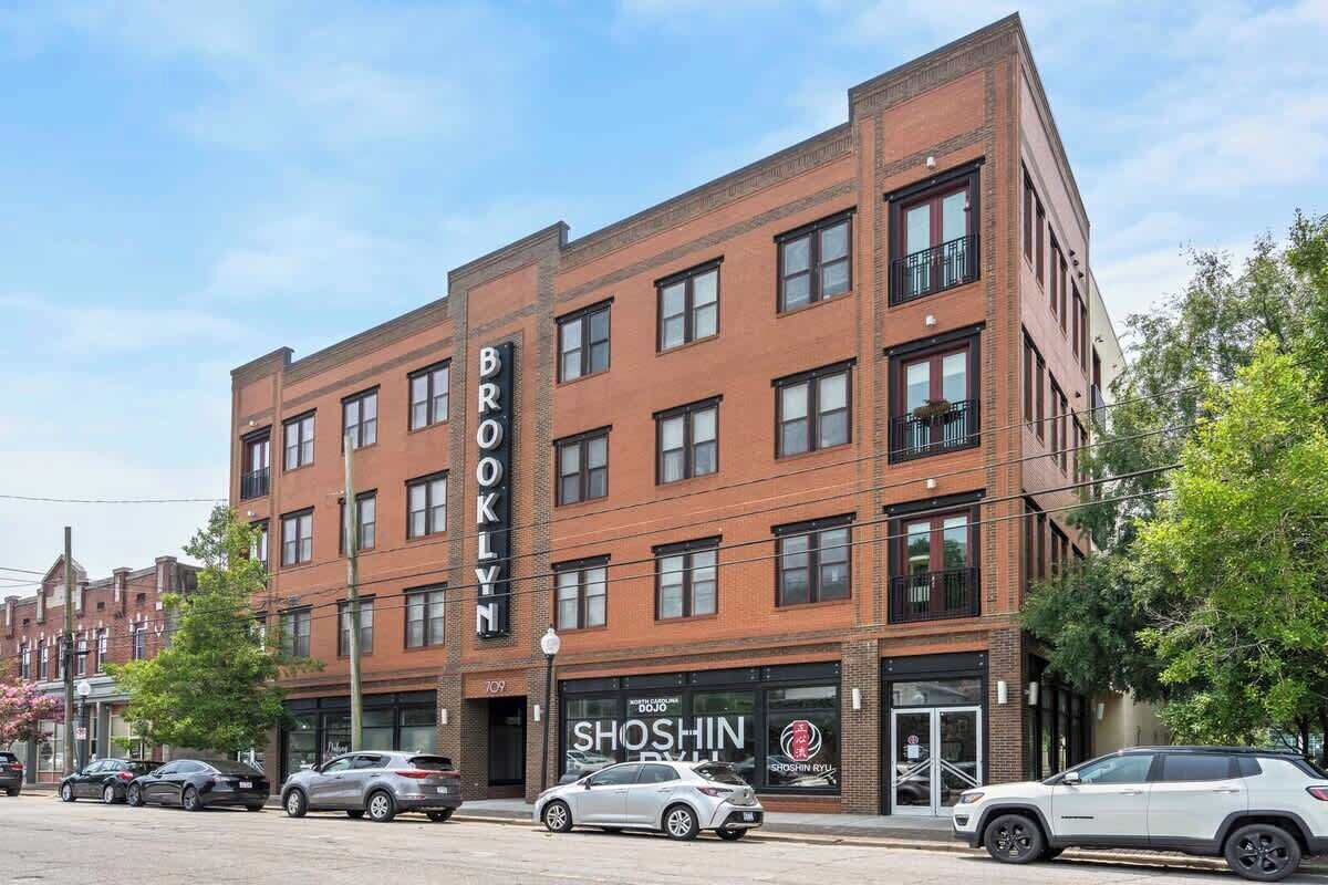 Un immeuble en briques de plusieurs étages, avec le nom « BROOKLYN » inscrit sur la façade.