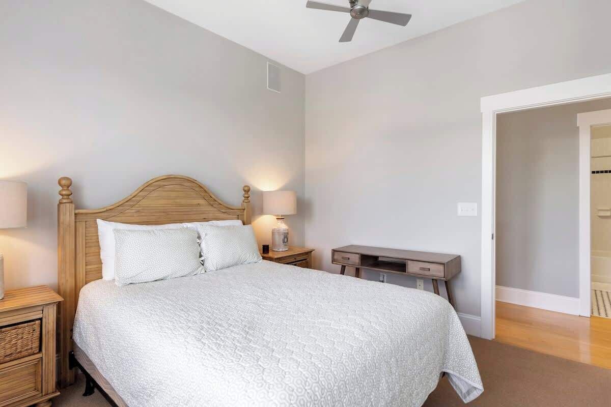 Une chambre à coucher avec un lit en bois, deux lampes de chevet, une table de chevet et un ventilateur de plafond.