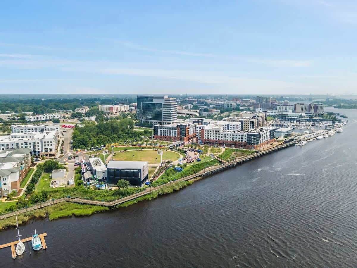 Vista aérea de una zona urbana frente al mar con edificios modernos, un puerto deportivo y un río.