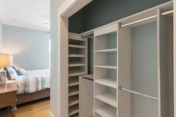 Un dormitorio con cama, mesita de noche y vestidor con estantes múltiples.