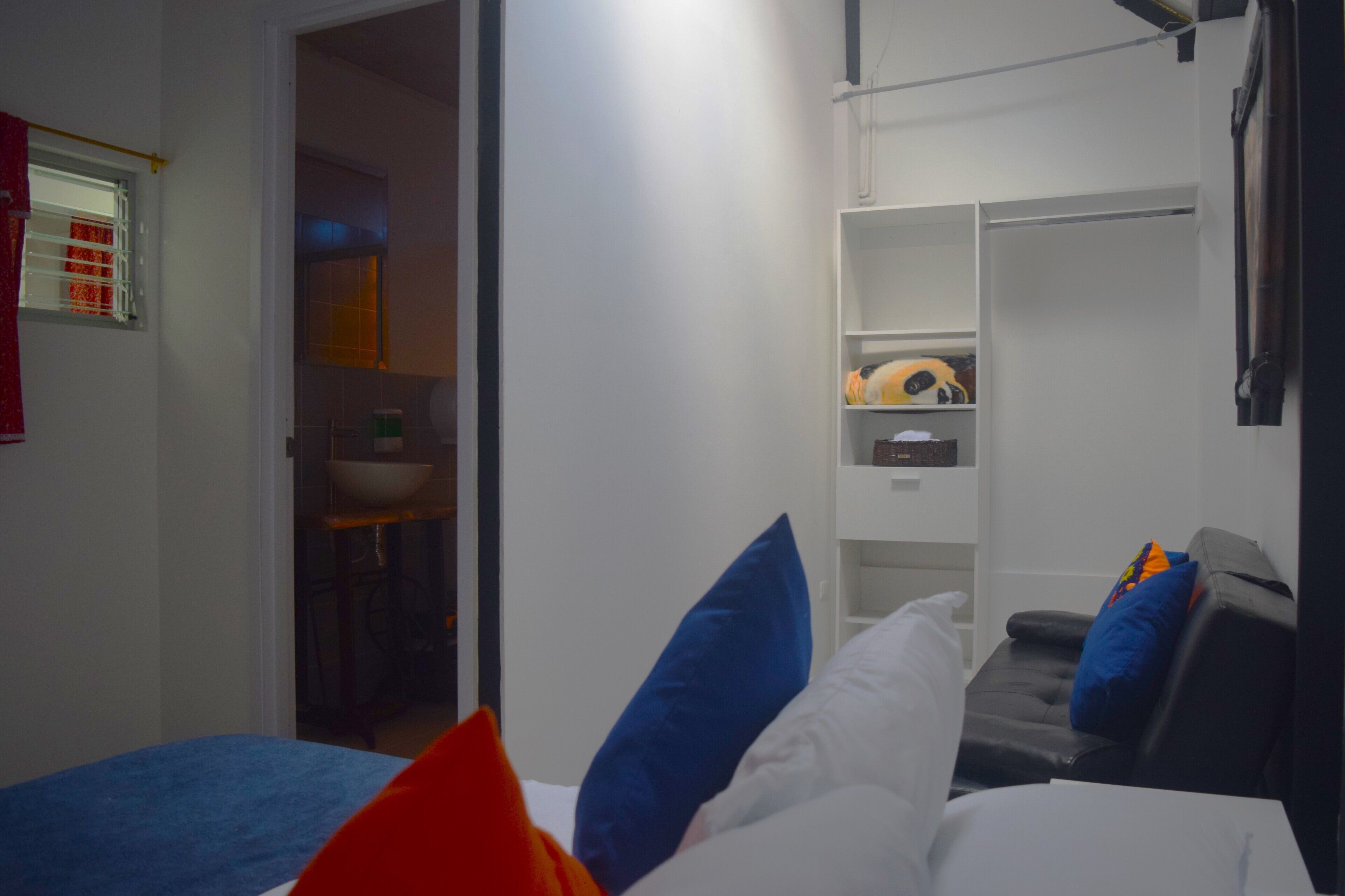 A bedroom with a bed, a wardrobe, and a small seating area.