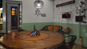 A round wooden table with chairs, a sign for 'Agora Cultural,' and a 'Flandia Hotel' sign on the wall. - Filandia Hotel (Filandia)