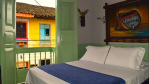 A room with a bed, a green door, a yellow wall, and a painting. - Filandia Hotel (Filandia)