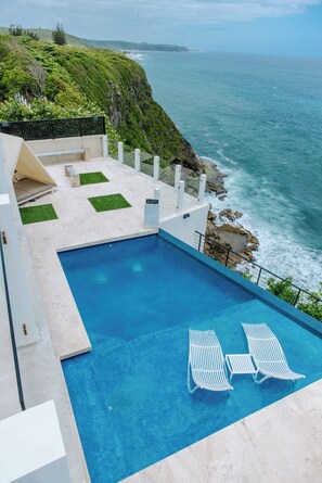 A swimming pool with lounge chairs and a view of the ocean. - Luxury Ocean View House (Quebradillas)