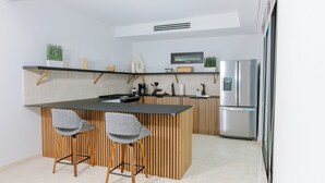Une cuisine moderne dotée d’un îlot central, de tabourets de bar, d’un réfrigérateur et d’un four encastré.