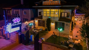 A two-story house with a visible balcony, a lawn with outdoor furniture, and a sign for "Black Lotus". - Black Lotus İzmir (Izmir)