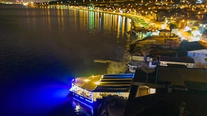 A waterfront hotel with a view of the water and city lights in the background. - Black Lotus İzmir (Izmir)