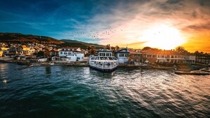 A waterfront town with a boat docked near buildings. - Black Lotus İzmir (Izmir)