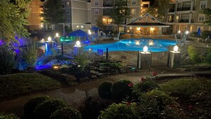 Une vue nocturne d’un hôtel doté d’une piscine, d’un éclairage extérieur et d’un jardin aménagé.