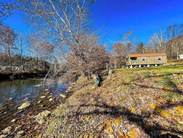 Une maison au bord d’une rivière, sous un ciel dégagé.