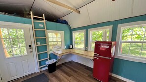 A compact kitchen with a wooden countertop, a red refrigerator, and a window overlooking greenery. - Meadow Riverfront Cabin
 (Nallen)
