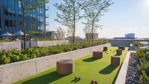 A rooftop garden with green artificial turf, seating areas, and a view of the city skyline. - Level Old Town - Spacious Studio Suite (Chicago)