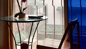 Een balkon met een glazen tafel, een potorkidee en een stoel.
