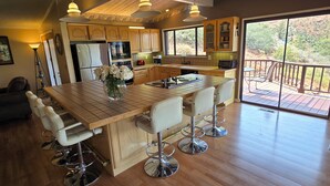 Une cuisine spacieuse dotée d’un grand îlot central, de meubles en bois et offrant une vue sur l’extérieur.