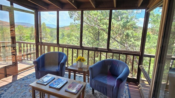 Un espace extérieur aménagé, abrité, avec deux fauteuils, une table basse et un ventilateur de plafond.