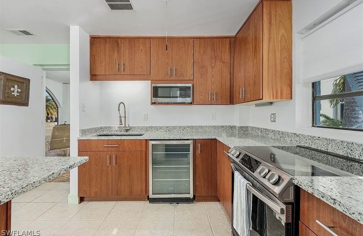 A modern kitchen with wooden cabinets, a built-in microwave, a refrigerator, and a stove.